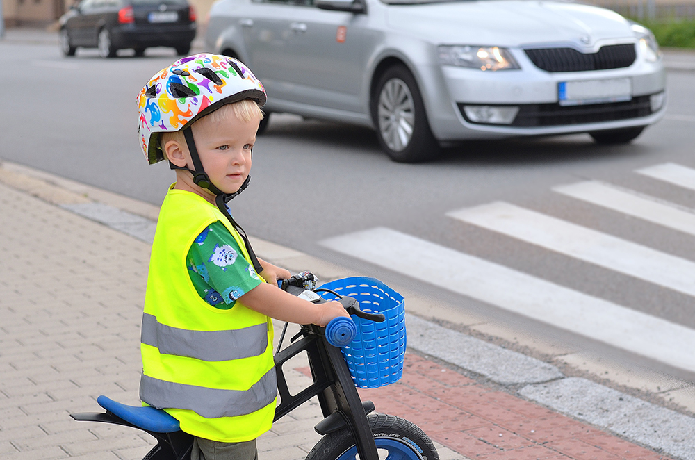 dziecko na rowerze w kasku i kamizelce
